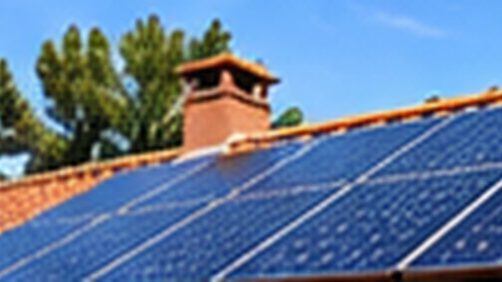 Panneaux solaires installés sur une toiture en tuiles sous un ciel bleu